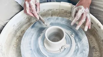 Pottery wheel forms a cylindrical clay container.
