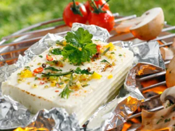 Gegrillter Käse mit Kräutern und Gemüse auf Folie.