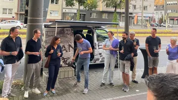 Gruppe von Menschen steht um einen Lieferwagen, offenbar feiernd.