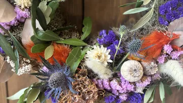 Bunter Kranz aus getrockneten Blumen und Blättern liegt.