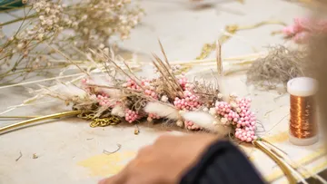 Flower arrangement is created on a table surrounded by materials.