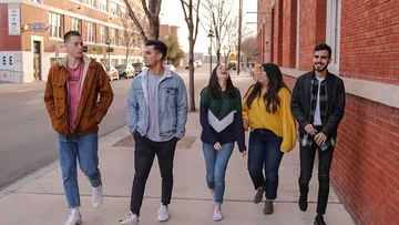 Five people walk down the street laughing.