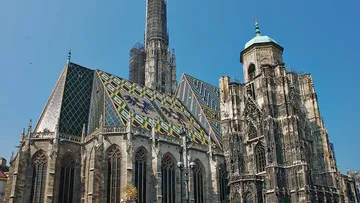Gotische Kathedrale mit buntem Dach unter klarem Himmel.