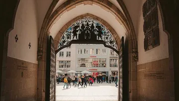 A gate opens, people walk in a city.