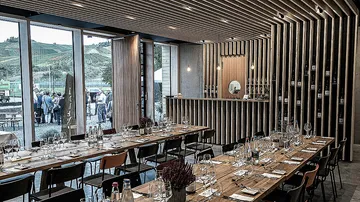 A modern restaurant with set tables and wine racks.