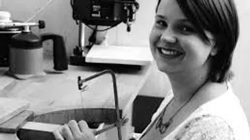 Woman smiles while working on a workbench.