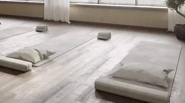 Yoga mats lie neatly on the wooden floor next to the window.