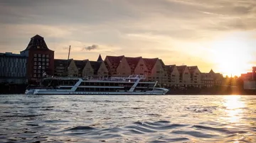 A ship sails on water as the sun sets.