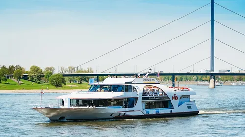 Ein Schiff fährt auf dem Fluss unter einer Brücke entlang.