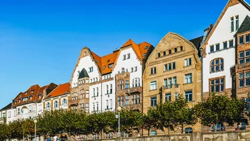 Reihenhäuser mit bunten Dächern, unter blauem Himmel.