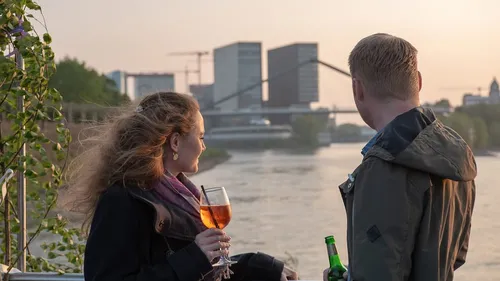 Zwei Personen schauen auf den Fluss bei Sonnenuntergang.