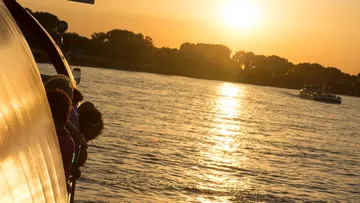 A boat sails on calm water at sunset.