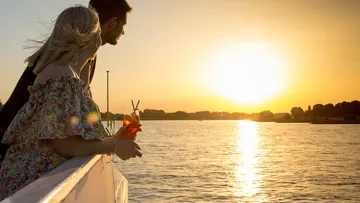 Ein Paar schaut auf den Sonnenuntergang über dem Wasser.