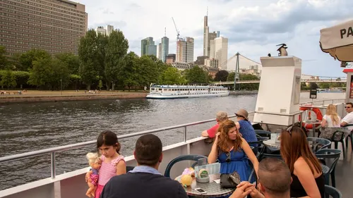 People sit on a boat as it passes by the shore.