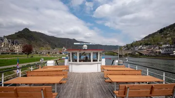 Boat dock with wooden tables, views of the river and hills.
