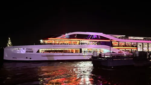 Ein Schiff legt nachts an mit bunten Lichtern.