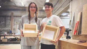 Two people present homemade wooden boxes
