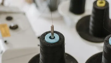 Nähmaschine mit Garnrollen und Faden in der Luft.