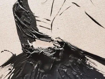 Schwarze Farbe fließt über eine helle Leinwand.