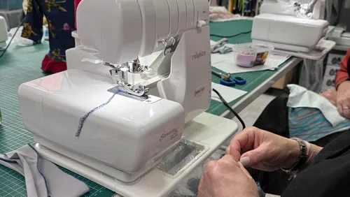 Nähmaschine näht Stoffteile in einem kreativen Umfeld.