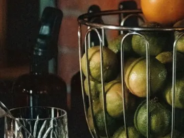 Woven basket with limes and an orange in it.