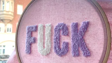 Embroidered letters form the word “FUCK” on fabric.