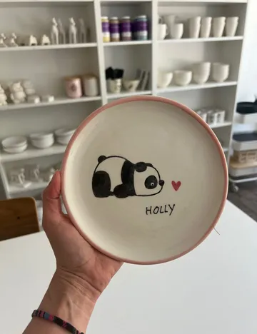 Hand holds a bowl with a panda design and “HOLLY.”