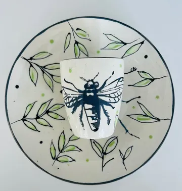 Bee-themed mug stands on a decorative plate.