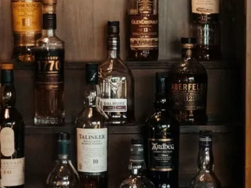Whiskey bottle arranged on a wooden shelf.