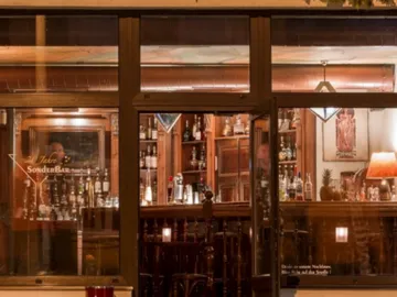 Bar with illuminated shelves, cozy atmosphere, alcoholic beverages.
