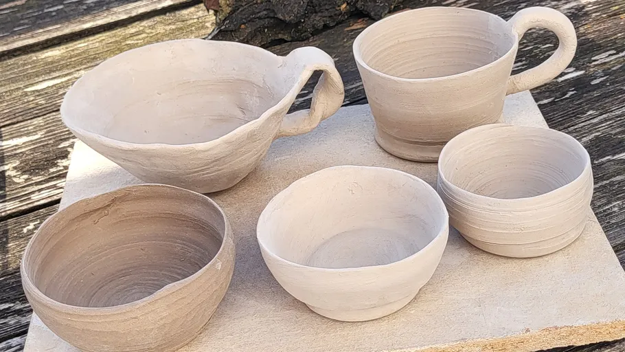 Clay pottery is lying on an outdoor work surface.