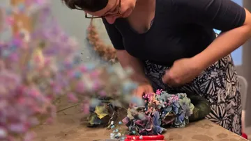 Woman arranging flowers on table.