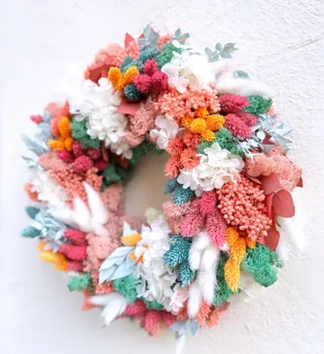 Colourful wreath of dried flowers hangs on the wall.
