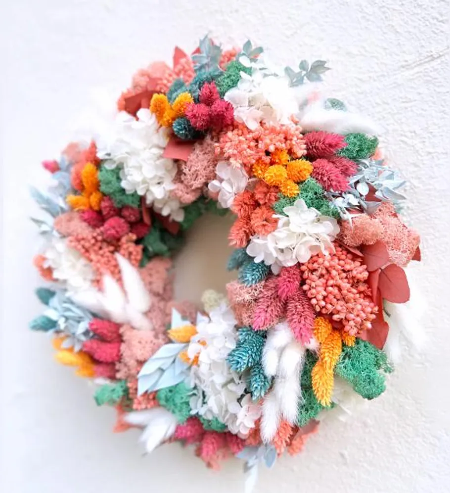 Colourful wreath of dried flowers hangs on the wall.