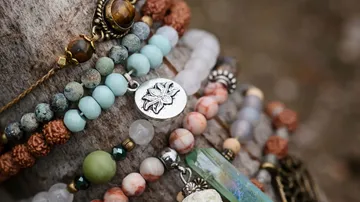 Mehrere bunte Armbänder liegen zusammen auf einem Baumstamm.