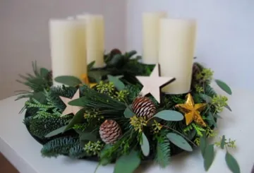 Adventskranz mit Kerzen, Tannenzweigen und goldenen Sternen.