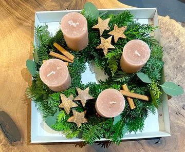 Adventskranz mit Kerzen, Holzsternchen und Zimtstangen dekoriert.