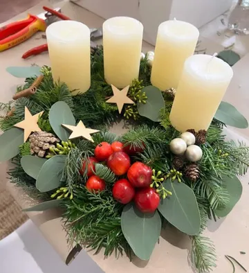 Christbaumkranz mit vier Kerzen, Beeren und Tannenzweigen.
