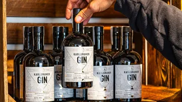 Flasche wird aus Regal mit Gin gehoben, Holzregal.
