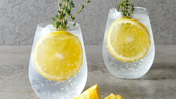 Two glasses of sparkling water, lemons and thyme.
