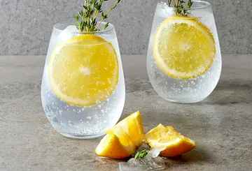 Zwei Gläser mit Limonade und Zitronenscheiben auf Tisch.