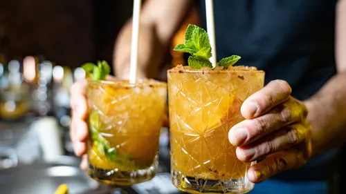 Two cocktails are held by one person, spearmint is decorated.