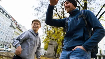 Zwei Personen lachen und gehen in einer Stadtstraße.