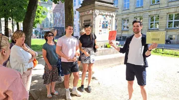 Gruppe Menschen lauscht einem Redner im Freien, mit Schildern.