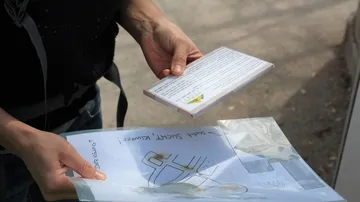 Eine Person hält Dokumente und eine CD im Freien.