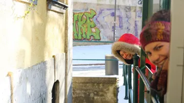 Zwei Frauen in Winterkleidung stehen lachend hinter einem Geländer.