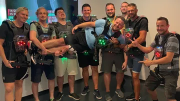 Gruppierung von Männern in Laser-Tag-Ausrüstung, posierend und lächelnd.