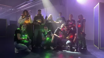Gruppe mit Lasertag-Waffen in einem beleuchteten Raum.
