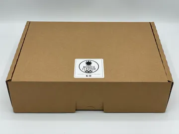 Braune Box liegt offen mit einem Aufkleber darauf.