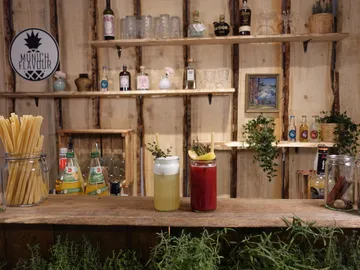 There are two drinks on a wooden counter in a bar.